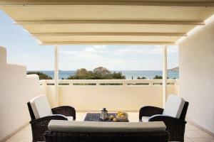 a patio with a table and chairs and a view of the ocean at Aithra -Agios Petros Andros in Gavrio