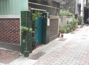 eine Ziegelwand mit einer blauen Tür mit Pflanzen drauf in der Unterkunft HouseNandoor in Tainan