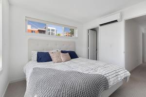 a white bedroom with a large bed with blue pillows at Deactivated- Rooftop Patio with Grill 2BR 3BA Central, Walkable Location in Seattle