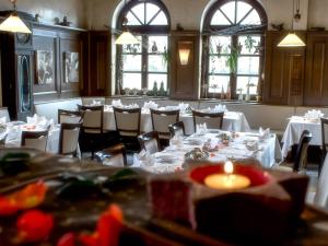 un comedor con mesas y sillas blancas y ventanas en Hotel Brößler, en Stockstadt am Main