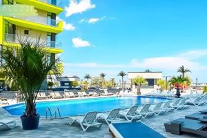 a swimming pool with chairs and a building at Alezzi Beach Resort - Sea View Suite in Mamaia Nord