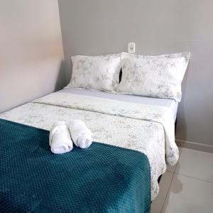 a bed with two white towels on a green blanket at Flat Temporada in Carolina
