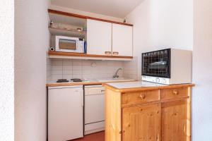 a small kitchen with white cabinets and a microwave at Bright Cocoon With Balcony And View On The Valley in Courchevel