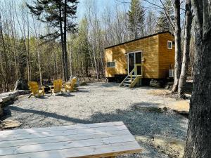 a wooden cabin in the woods with a table and chairs at Trailside Stays in Rumney