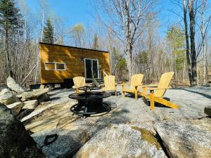 a log cabin with chairs and a fire pit at Trailside Stays in Rumney