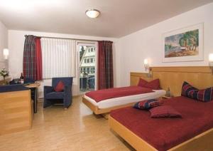 a hotel room with two beds and a chair at Pension Gästehaus Kachelofa in Vaihingen an der Enz