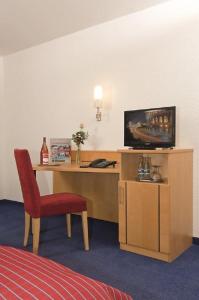 ファイインゲン・アン・デア・エンツにあるPension Gästehaus Kachelofaのデスク、テレビ、椅子が備わる客室です。