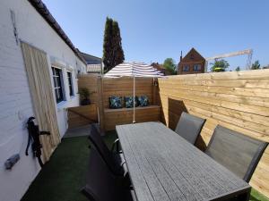 a patio with a table and an umbrella at Le petit blanc in De Haan