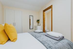 a white bedroom with a large white bed with yellow pillows at Cosy 2nd Floor Apartment - King Size Bed & Free Parking in Nottingham