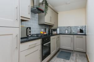 una cocina con armarios blancos y encimeras negras en Cosy 2nd Floor Apartment - King Size Bed & Free Parking en Nottingham