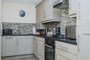 a kitchen with white cabinets and black counter tops at Spacious 2nd Floor Apartment - King Size Bed & Free Parking in Nottingham