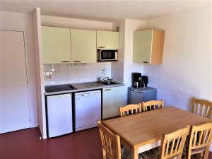a kitchen with a wooden table and a table and chairs at Appartement 2 Pièces pour 6 Personnes – Résidence Les Chalets d'Aurouze, La Joue du Loup - FR-1-504-464 in Le Dévoluy
