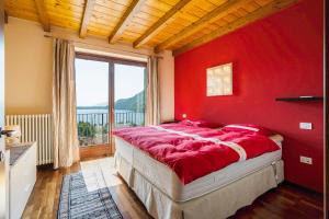 a red bedroom with a bed with a large window at Casa Marina in Mergozzo