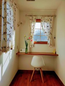 ein Fenster mit einem Stuhl und einer Vase aus Blumen in einem Zimmer in der Unterkunft Guest house with host Takao SORA- Vacation STAY 13000 in Hachioji