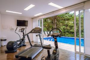 a gym with cardio machines and a swimming pool at Aconchegante apartamento em Campos do Jordão, região Capivari - PET friendly# in Campos do Jordão