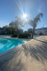 een zwembad met palmbomen en de zon bij A un passo dal mare - Costa Ripagnola in Spiaggia di Conversano