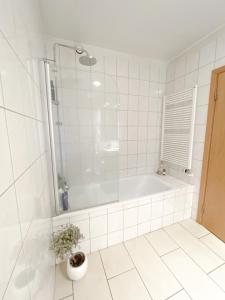 ein weißes Badezimmer mit einer Badewanne und einer Topfpflanze in der Unterkunft Lovely 2-bed apartment with everything you need. in Reykjavík