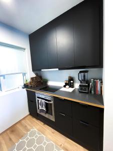 eine Küche mit schwarzen Schränken und einem Herd in der Unterkunft Lovely 2-bed apartment with everything you need. in Reykjavík