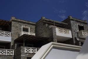 a brick building with white windows and a blue sky at Aithra -Agios Petros Andros in Gavrio