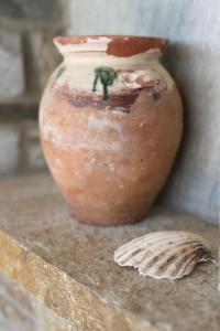 a vase sitting on a ledge next to a leaf at Aithra -Agios Petros Andros in Gavrio