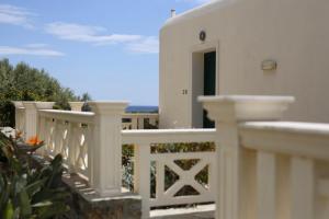 a white house with a white fence and a door at Aithra -Agios Petros Andros in Gavrio