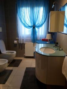 a bathroom with a sink and a toilet and blue curtains at Casa Rosa dei Venti in Cividale del Friuli