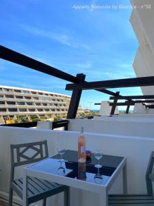 a table with two glasses and a bottle of wine on a balcony at Studios Port Nature village Naturiste in Cap d'Agde