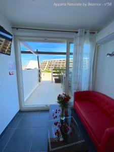 sala de estar con sofá rojo y mesa de cristal en Studios Port Nature village Naturiste, en Cap d'Agde