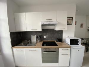 eine Küche mit weißen Schränken und einer Spüle in der Unterkunft Appartement Rénové avec Cuisine Américaine et WIFI, Proche des Thermes Saint Roch - FR-1-541-32 in La Roche-Posay