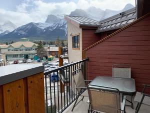 a balcony with a table and chairs and mountains at Alluring Mountain View Condo -Right In The Heart Of Downtown!! Hosted by Fenwick Vacation Rentals in Canmore
