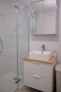 a white bathroom with a sink and a shower at Apartment House Bucul in Mali Lošinj