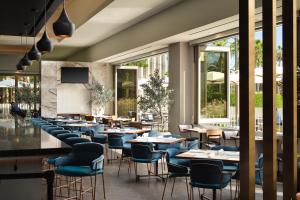 ロサンゼルスにあるHyatt House LAX Century Blvdのテーブルと椅子と窓のあるレストラン
