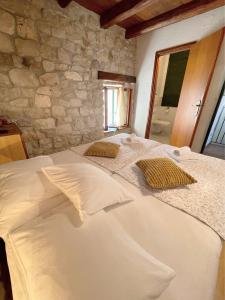 Cette chambre dispose d'un grand lit blanc et d'un mur en pierre. dans l'établissement House Ivancic, à Trogir
