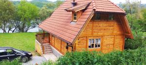 een houten huis met een auto ervoor geparkeerd bij Drinska Tisina in Ljubovija