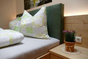 uma cama com almofadas e um vaso de plantas sobre uma mesa em Der Luemerhof em Marlengo