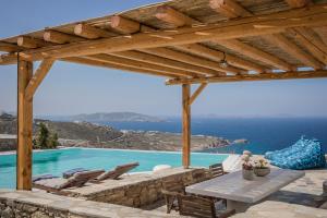 Villa Argo by Mykonos Top Villas في Houlakia: فناء مع طاولة وكراسي ومسبح
