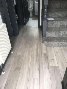 a hallway with a wooden floor with a toilet and stairs at White Shelf Dartford House in Kent