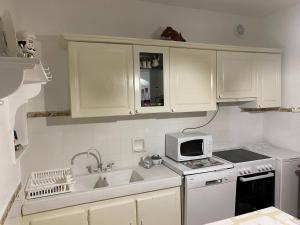 eine weiße Küche mit einer Spüle und einer Mikrowelle in der Unterkunft Villa Quiberon, 5 pièces, 8 personnes - FR-1-478-170 in Quiberon