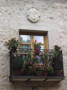 a window with a balcony with flowers and a clock at La Posada de Tamajon in Tamajón