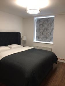 a bedroom with a black bed and a window at VICTORIA PLACE in Belfast