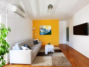 sala de estar con sofá blanco y pared de acento amarillo en Apartment Violetta-Punta en Umag