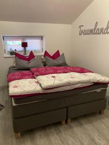 een slaapkamer met een bed met rode lakens en kussens bij Feriennest Chiemseeglück in Übersee