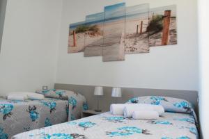 una camera con due letti e un dipinto di una spiaggia di Akoya Apartments a San Vito lo Capo