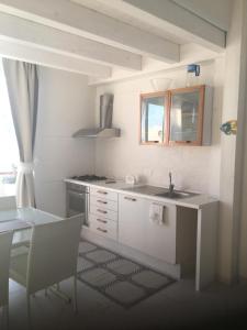 cocina blanca con fregadero y mesa en Le Muse casa vacanze, en Scoglitti