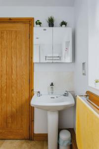 a bathroom with a white sink and a wooden door at 2 Bedroom Garden Apartment Near QMC, Tennis Centre & City in Nottingham