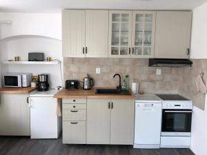 una cocina con armarios blancos y electrodomésticos blancos en SWEET HOME, en Krásná Lípa