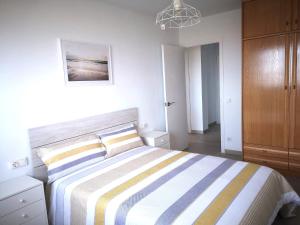 - une chambre avec un grand lit et une couverture rayée dans l'établissement ÁTICO FRENTE AL MAR, à Canet de Mar
