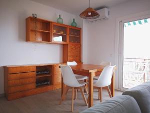 comedor con mesa de madera y sillas blancas en ÁTICO FRENTE AL MAR en Canet de Mar