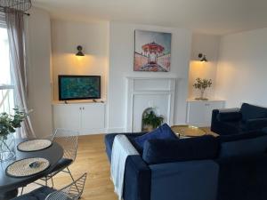 a living room with a blue couch and a tv at Seaview flat with balcony, spacious 2 bedroom in Worthing