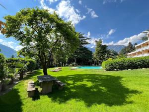 a park with a bench and a tree and a pool at Garden Pool Apartment in Merano
